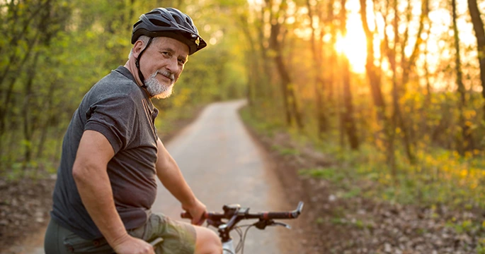 senior man riding a bike on a trail